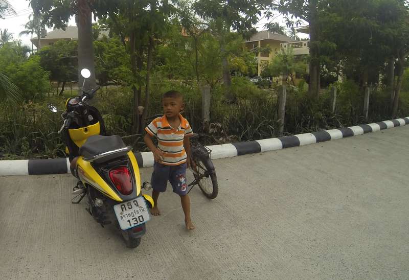 A little boy shortly after parking his little bike. 